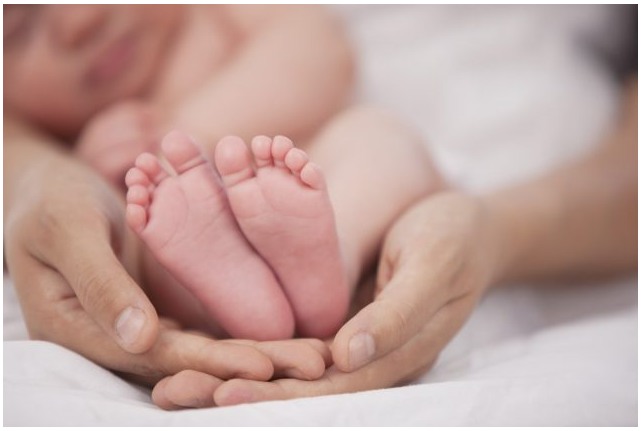 Decorative - closeup of a mother's hands cradling a sleeping baby with a focus on their tiny feet.