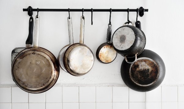 Pots and pans hanging from a kitchen rack.